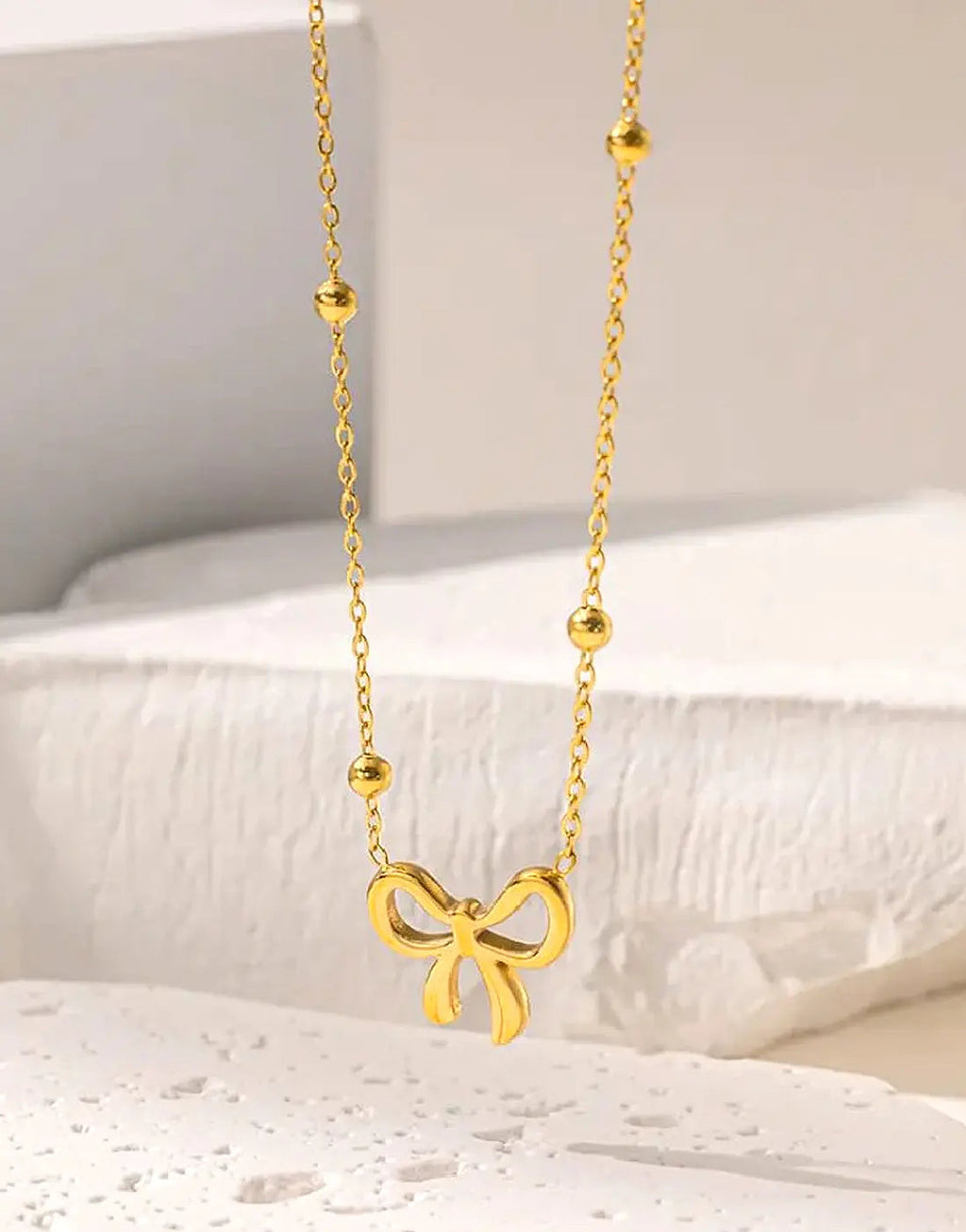 Simple Bowelle Necklace by Glitze Accessories featuring a delicate chain with a small bow pendant.